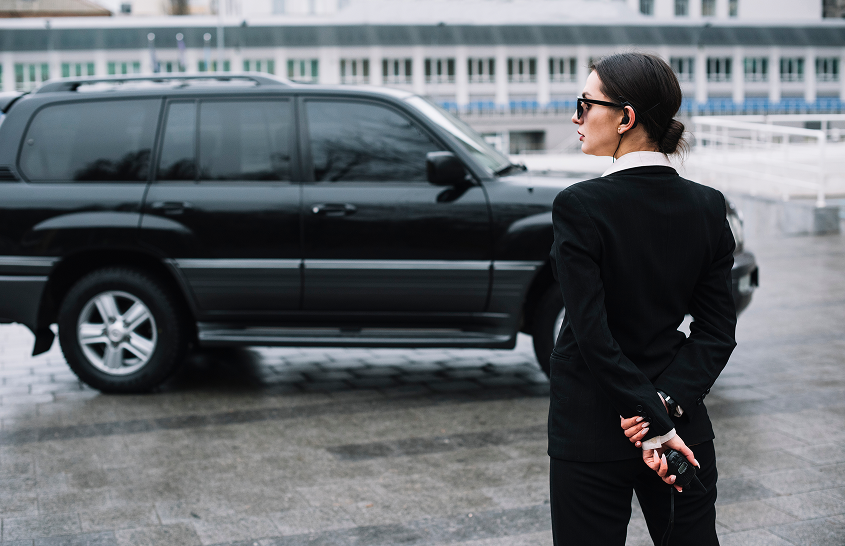 security woman standing in front of a car